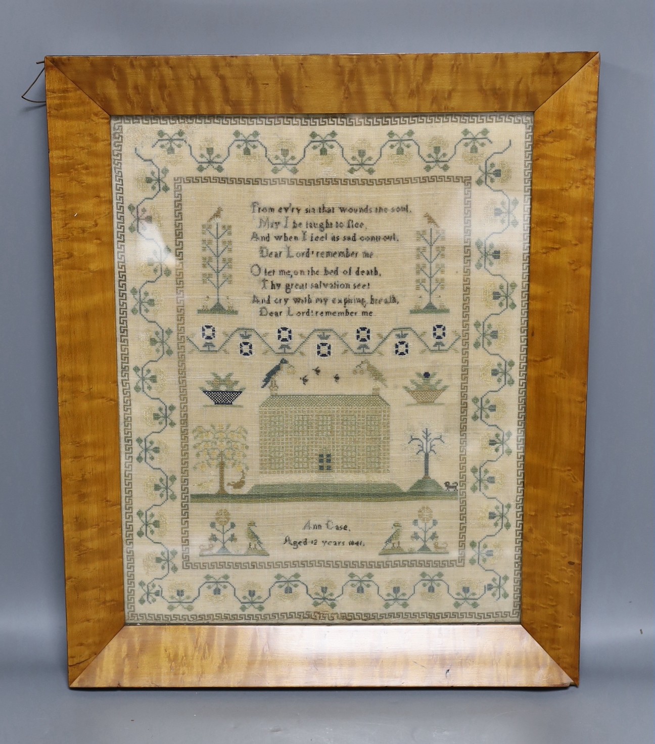 An early Victorian sampler, dated 1841 by Ann Case, embroidered with a house, trees, a dog and birds, in Maple frame, 42cms wide x 51cms high (including frame)